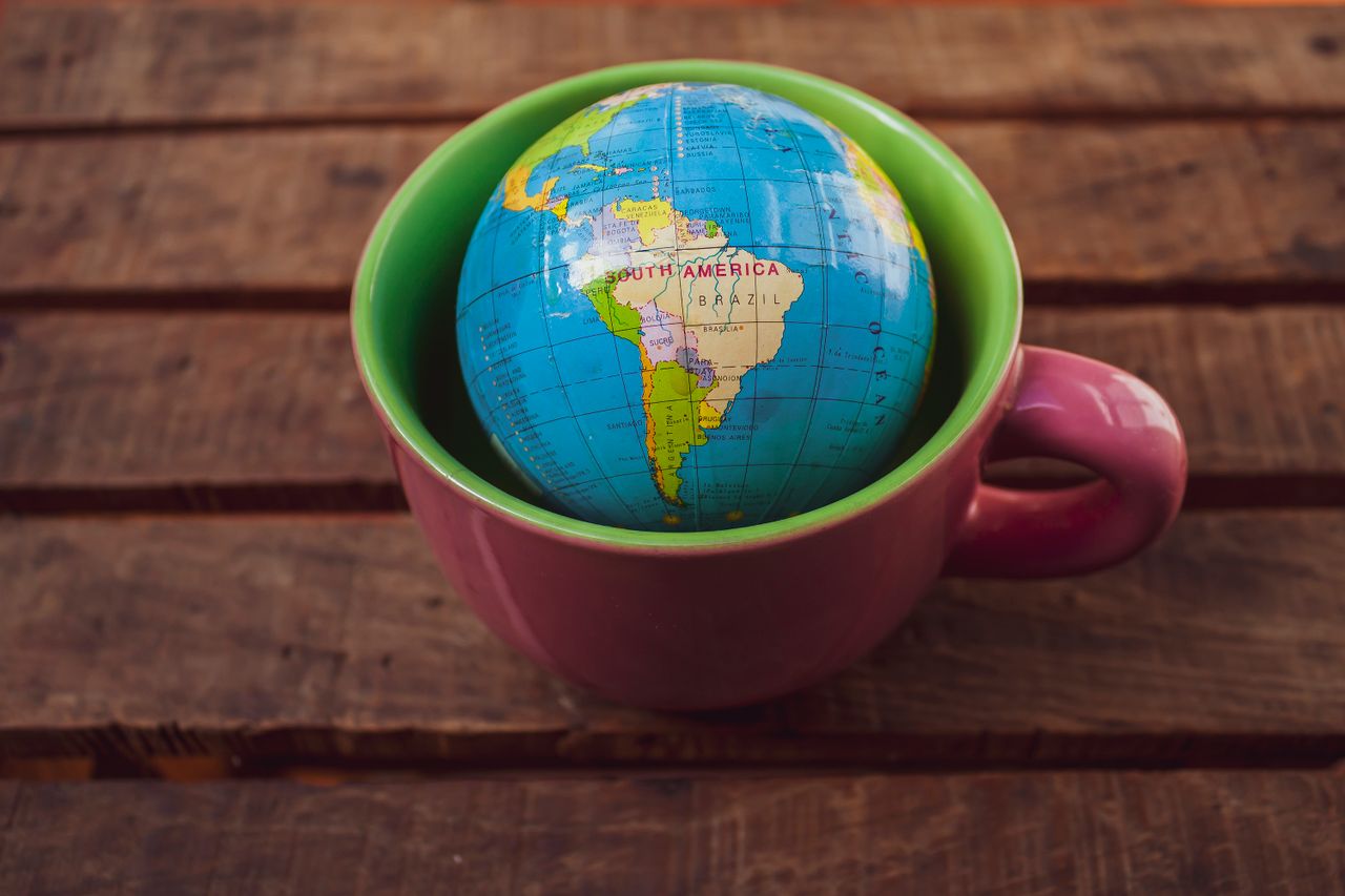 A vibrant globe inside a mug placed on a rustic wooden surface, symbolizing global travel.