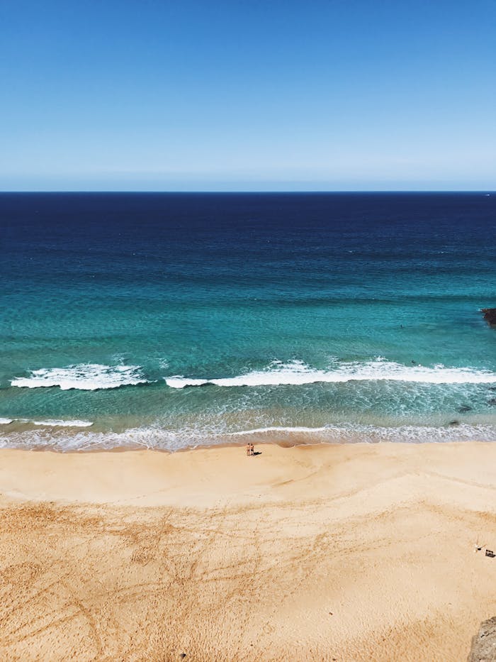 A serene view of La Oliva beach with clear skies and turquoise waters, perfect for relaxation.